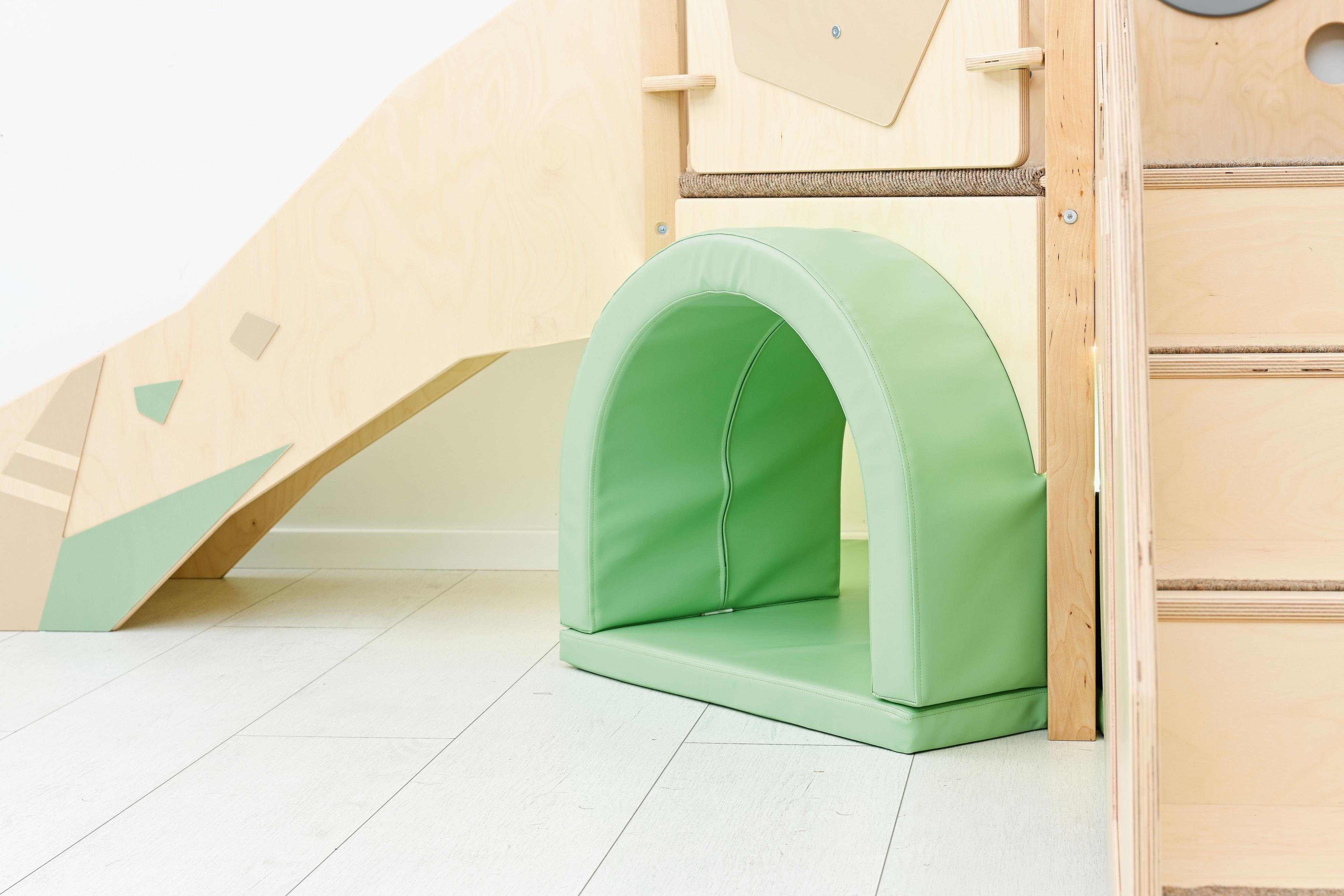 Sensorische Spielecke mit Hochebene und grünem Tunnel.