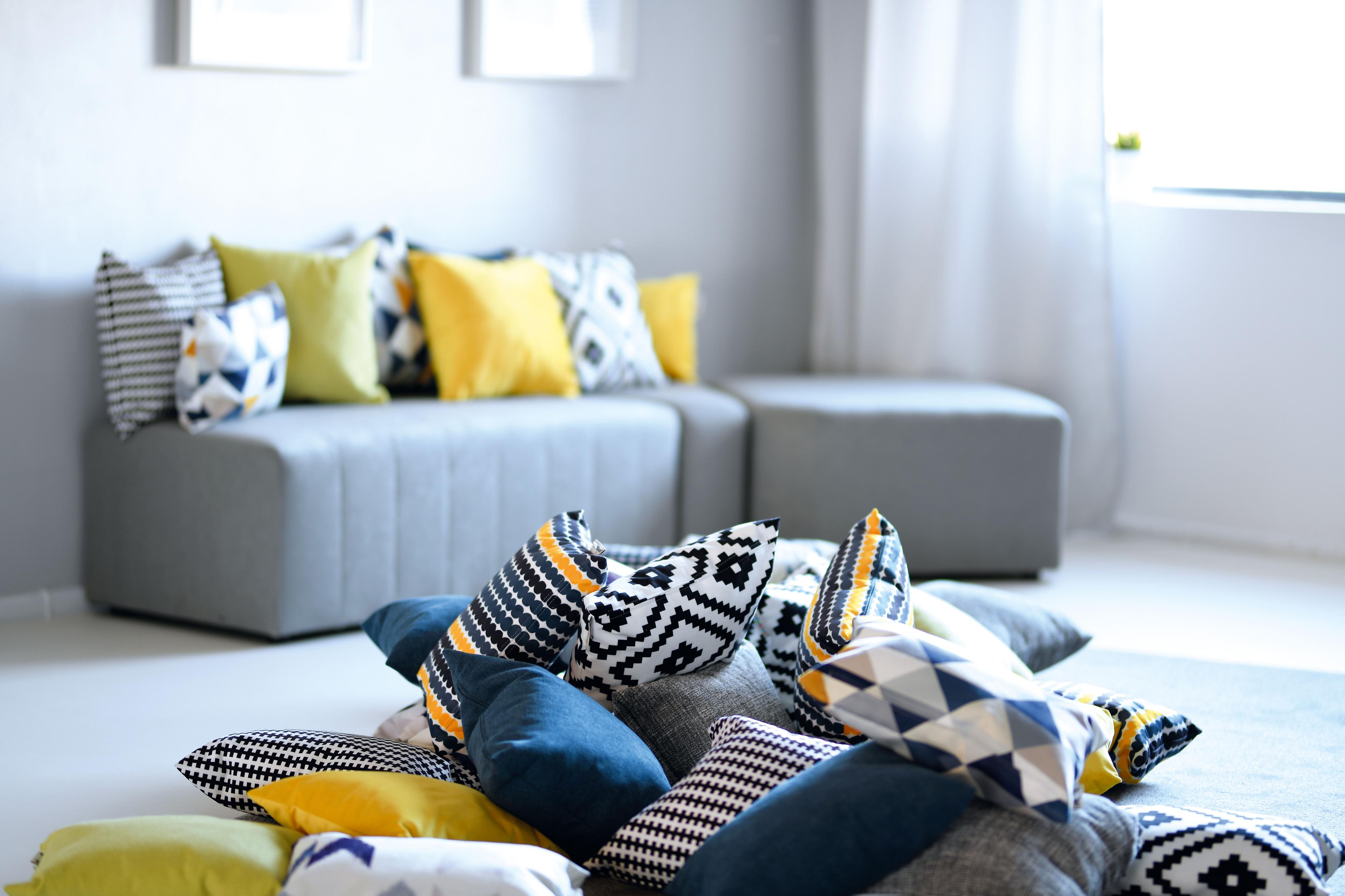 Bunte Kissen für Sitzlandschaft auf grauer Couch platziert.