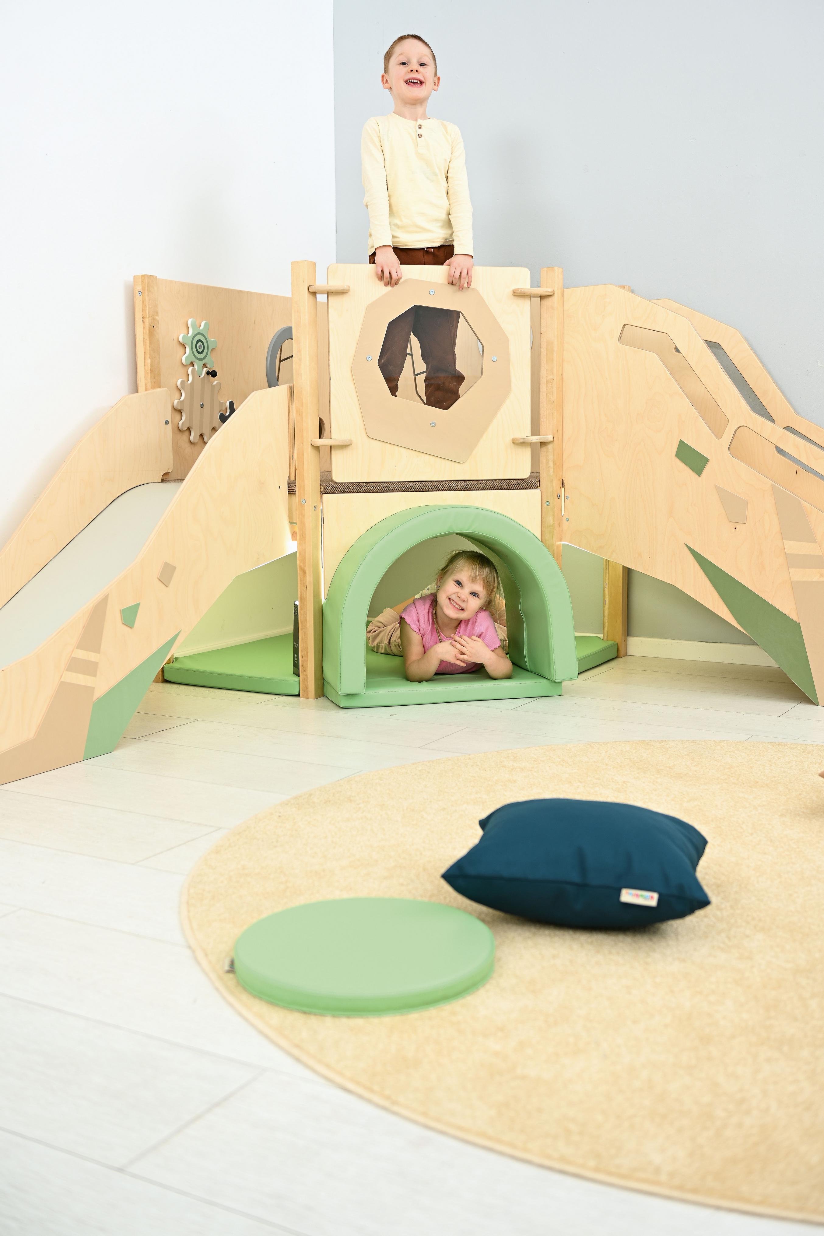 Sensorische Spielecke mit Hochebene und fröhlichen Kindern.