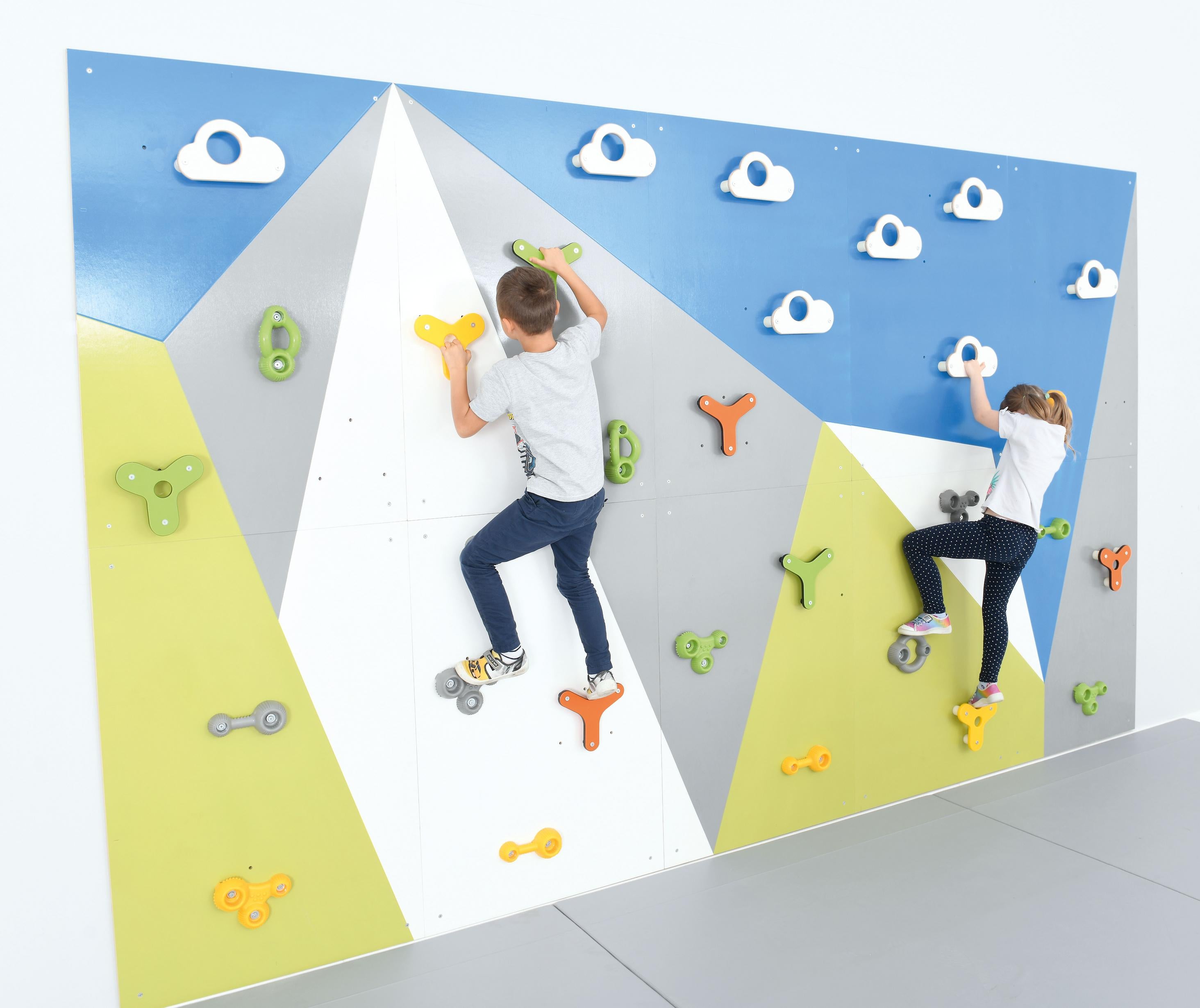 Bunte Kinder klettern auf der Kletterwand in Sporthalle.