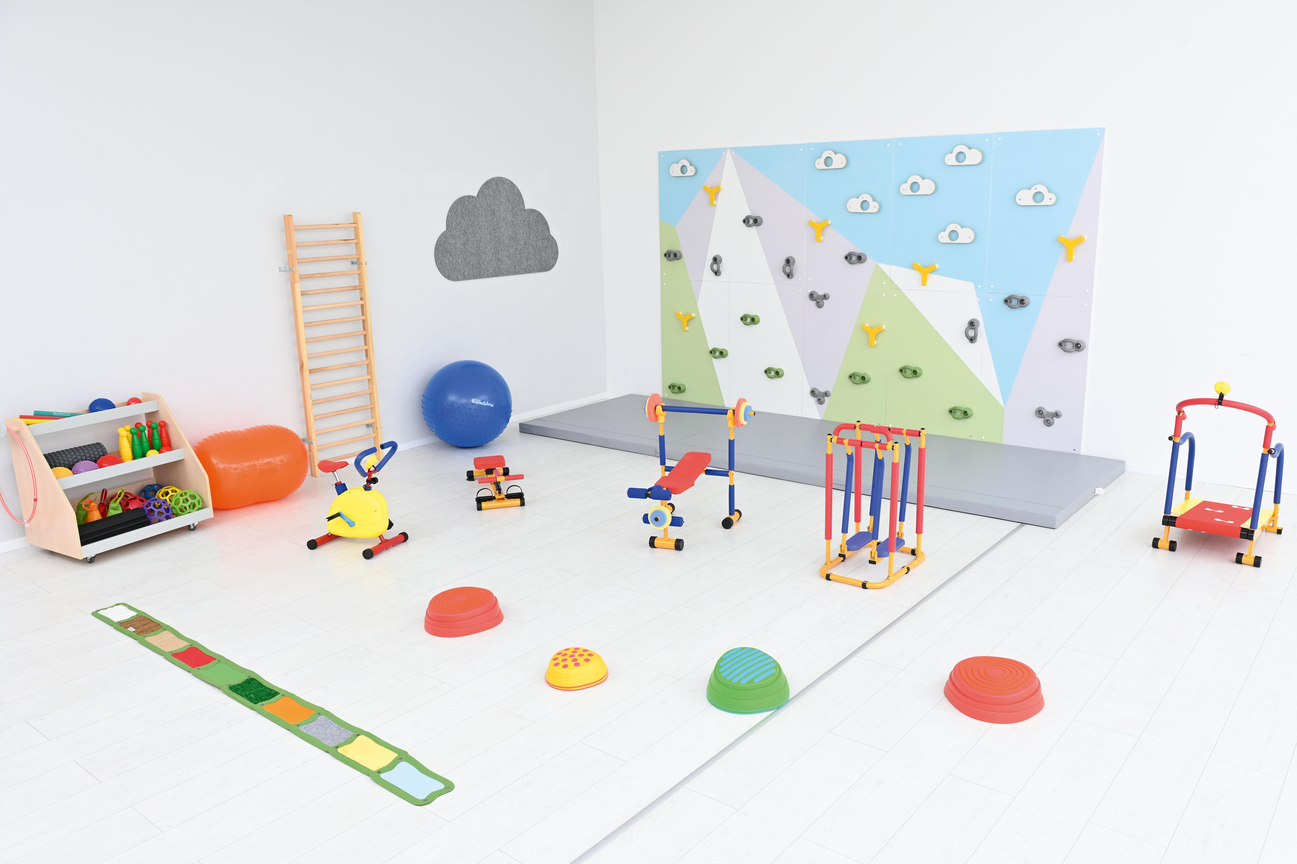 Bunte Kletterwand in Kita mit Spielgeräten und Matten.