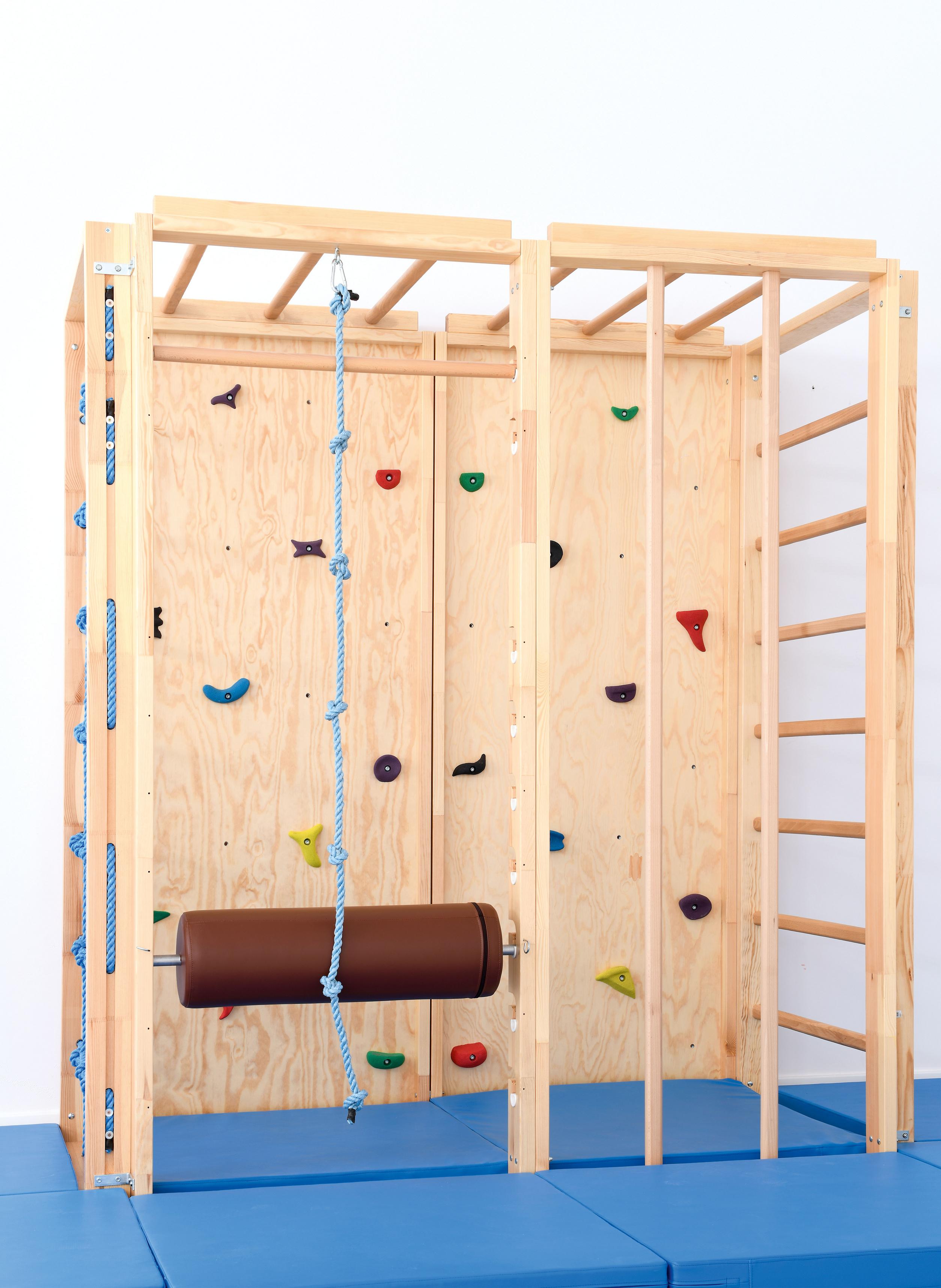 Holzkletterwand mit Griffen und Seil in Turnhalle.
