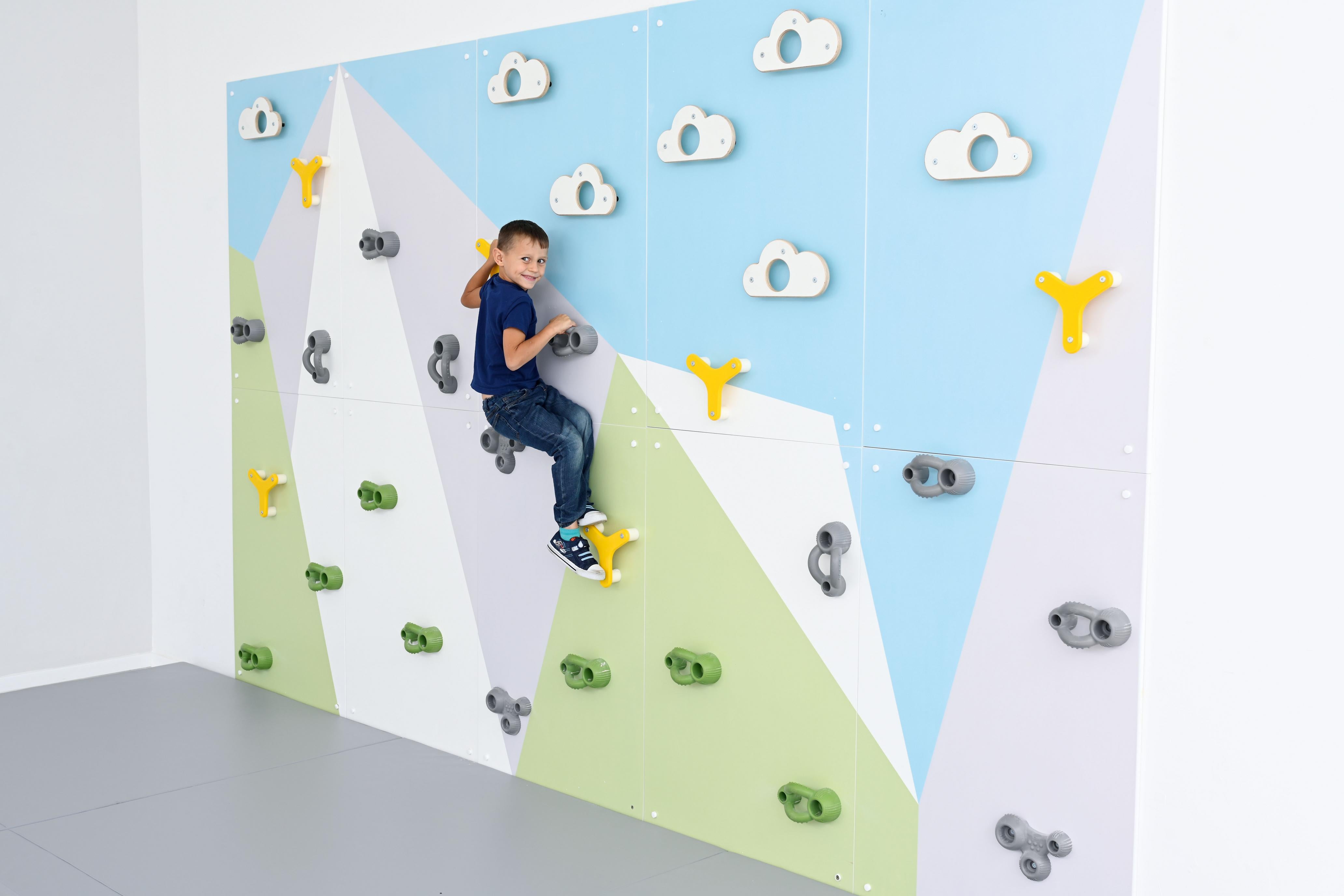 Kind klettert an bunter Kletterwand in Sporthalle.