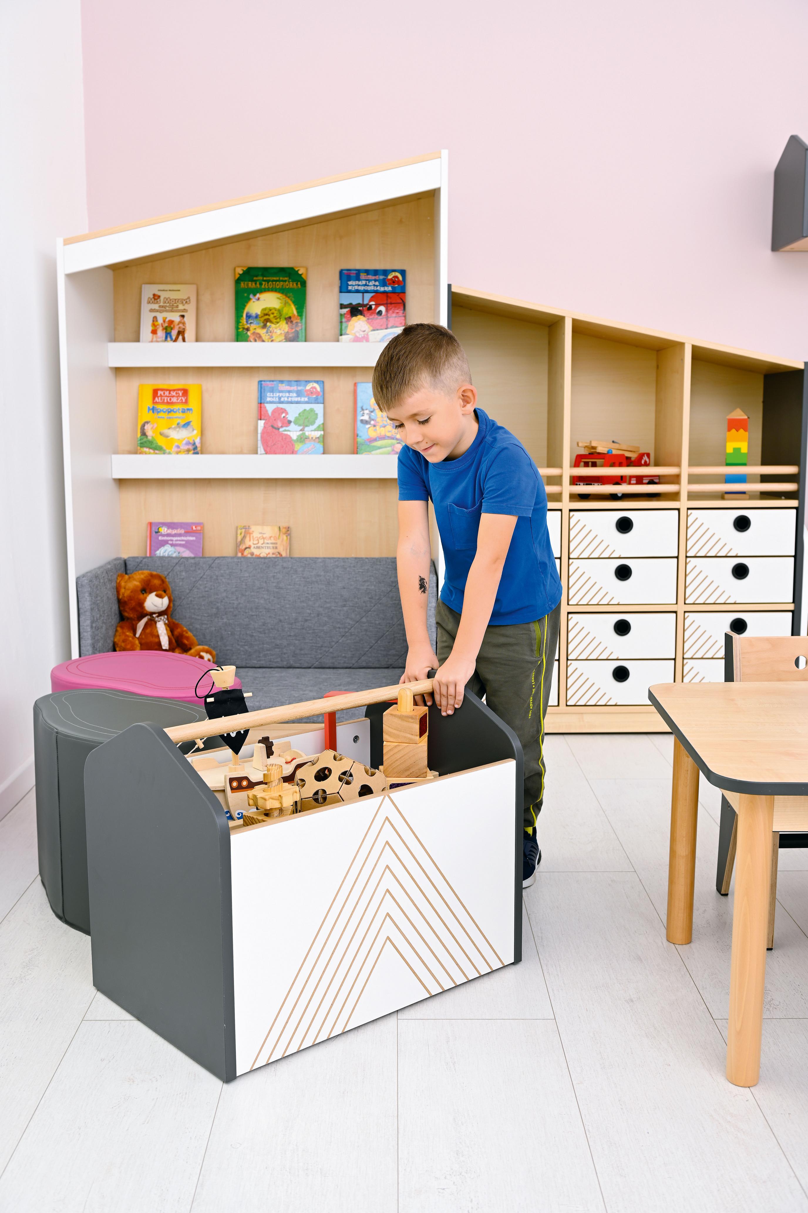 Kind spielt mit Rollbehälter für Bücher im Gruppenraum. - Produkt wird im Kindergarten oder Schule genutzt.