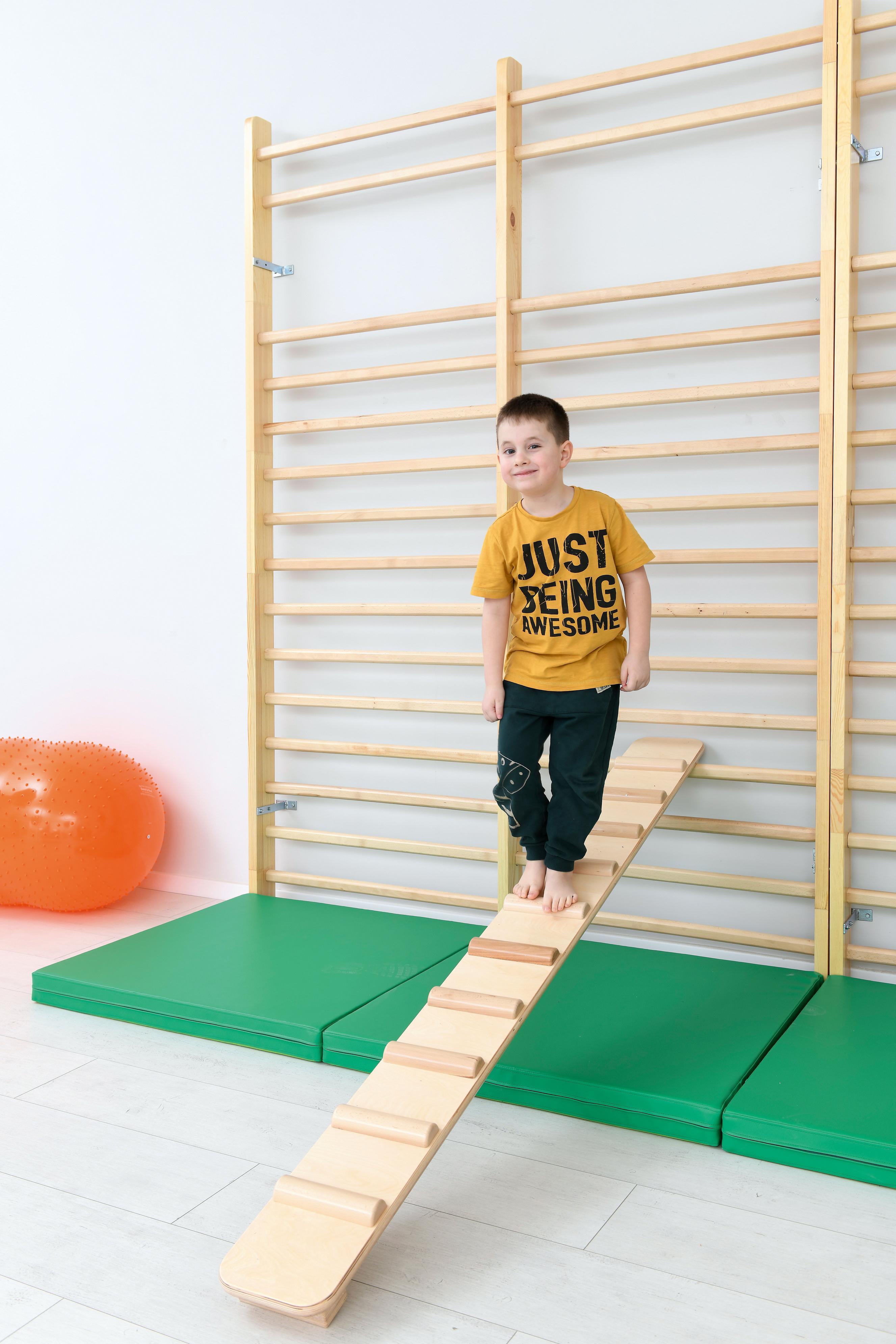 Kind steht auf einer doppelten Sprossenwand - 256 cm.