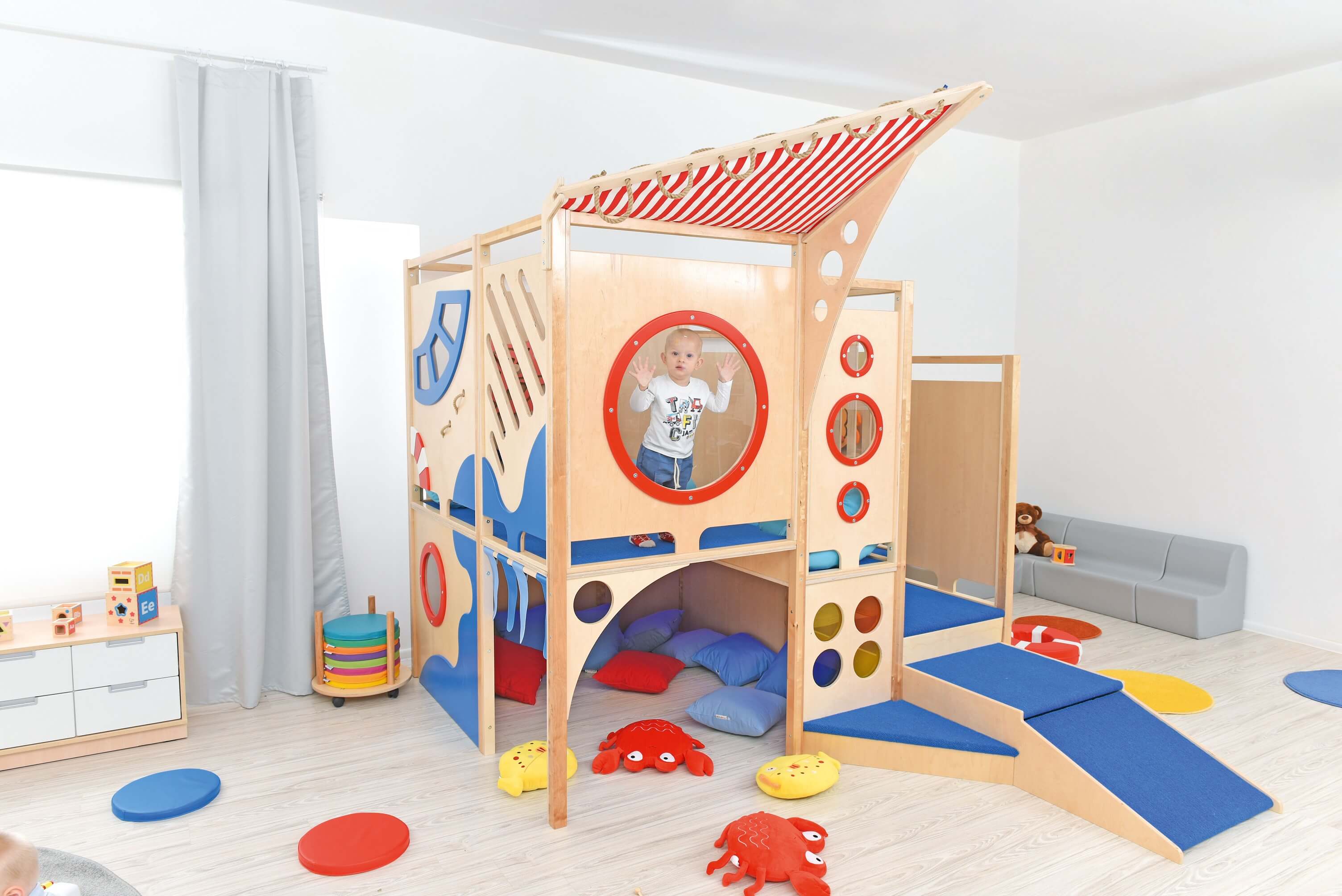 Kindergarten Spielburg Neptun im Gruppenraum von vorne links Kind guckt aus Fenster