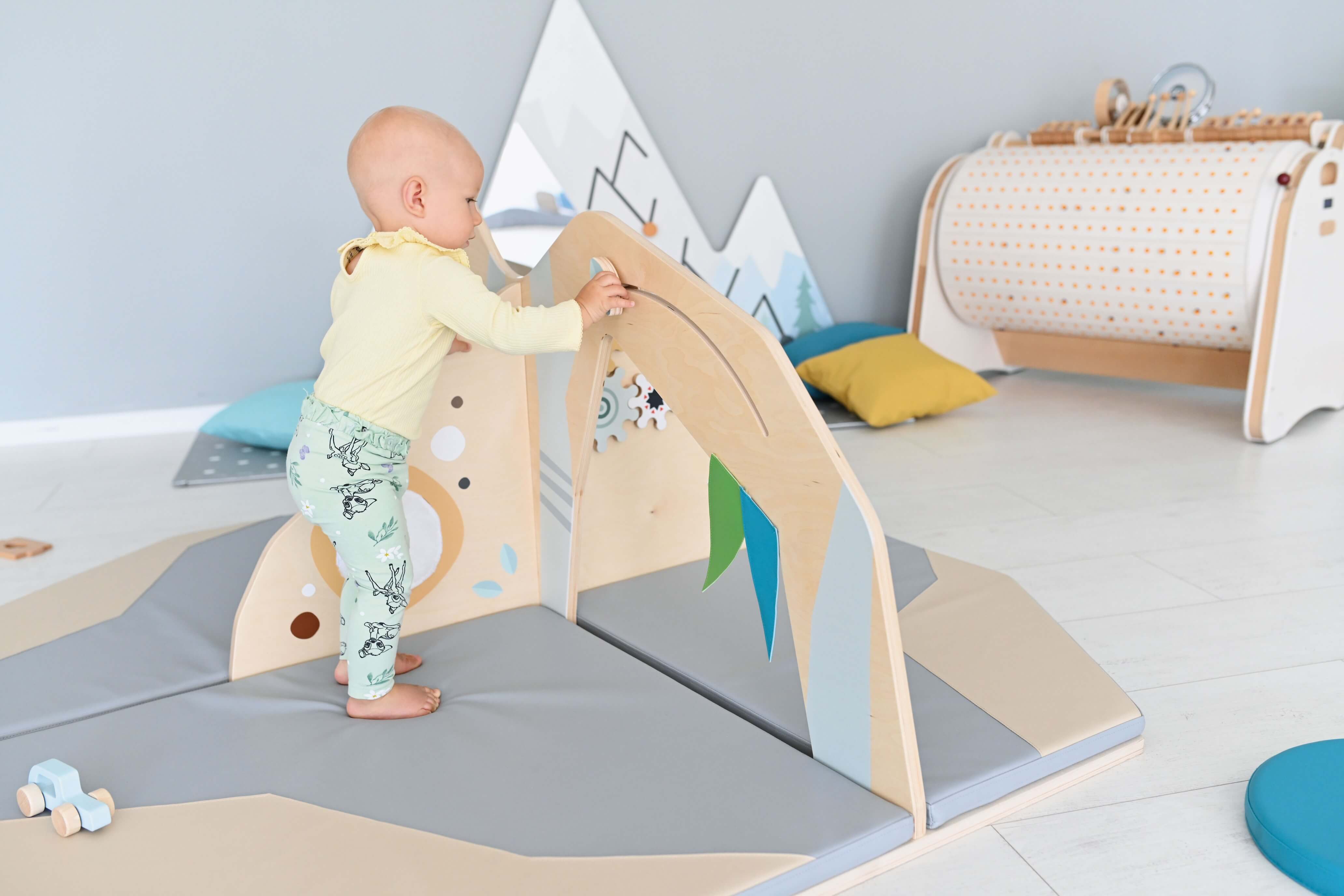 Kleinkindspielecke Bergwiese für Krippen und Kindergarten Krippenkind spielt an Motorikwand