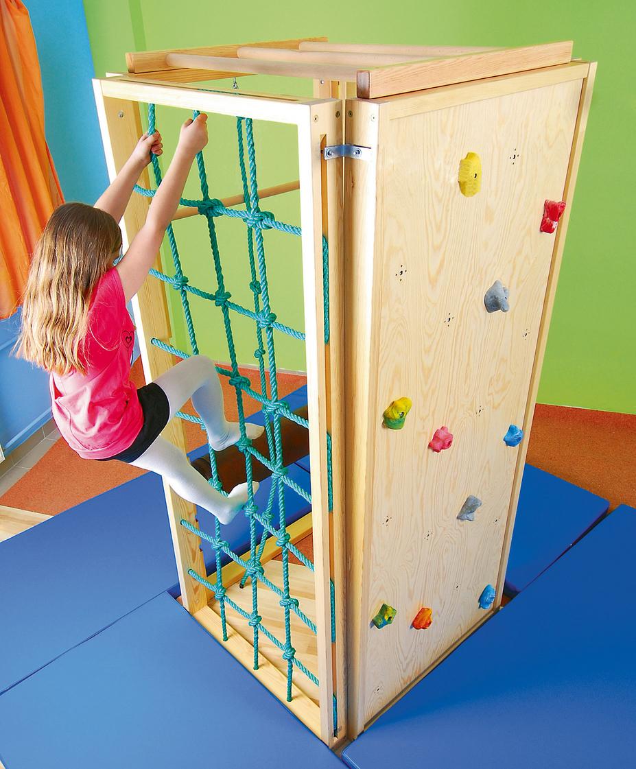 Mädchen klettert an Indoor-Kletterwand in der Turnhalle.