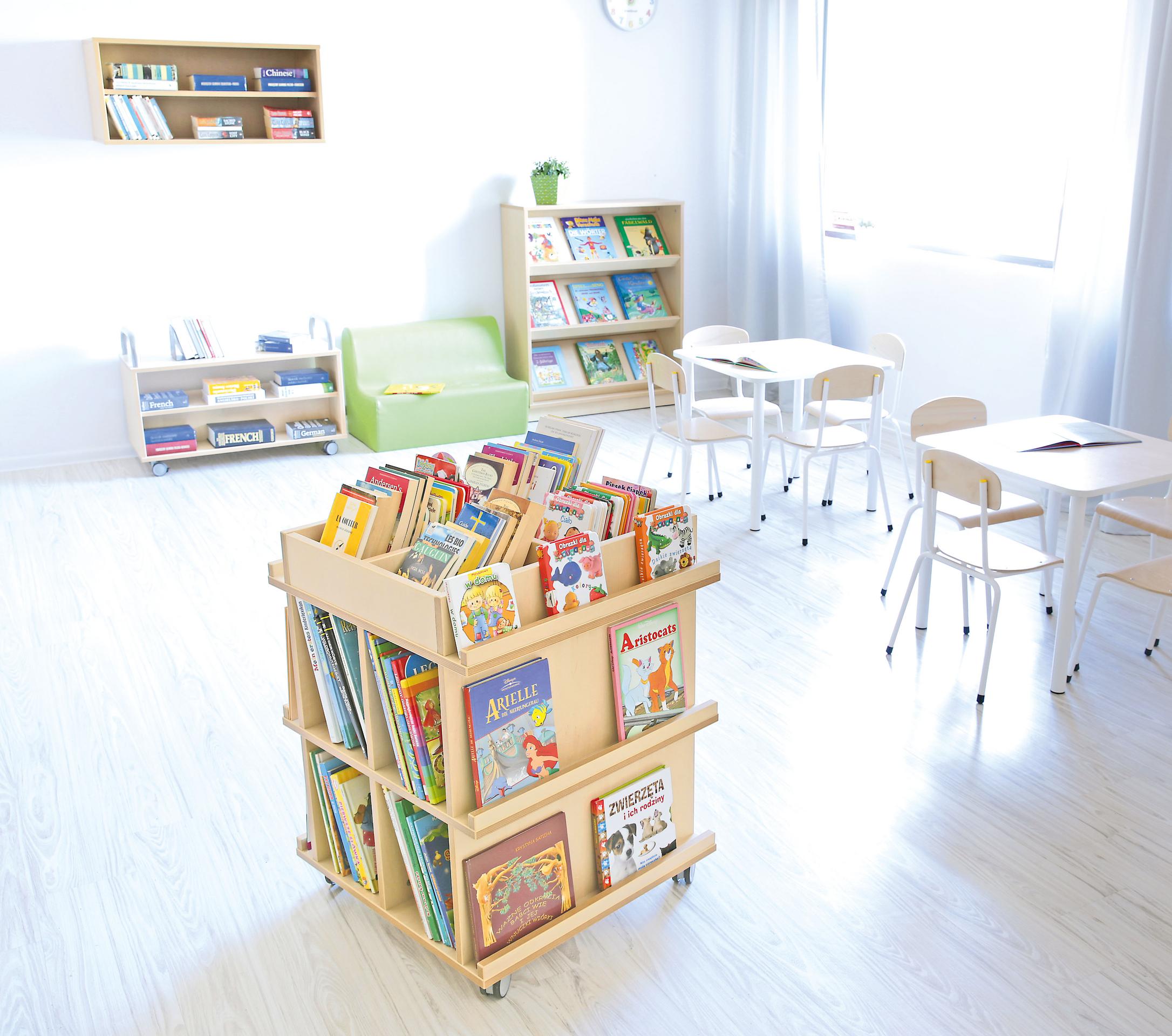 Mobiles Bücherregal in heller Leseecke mit Tischen. - Produkt wird im Kindergarten oder Schule genutzt.
