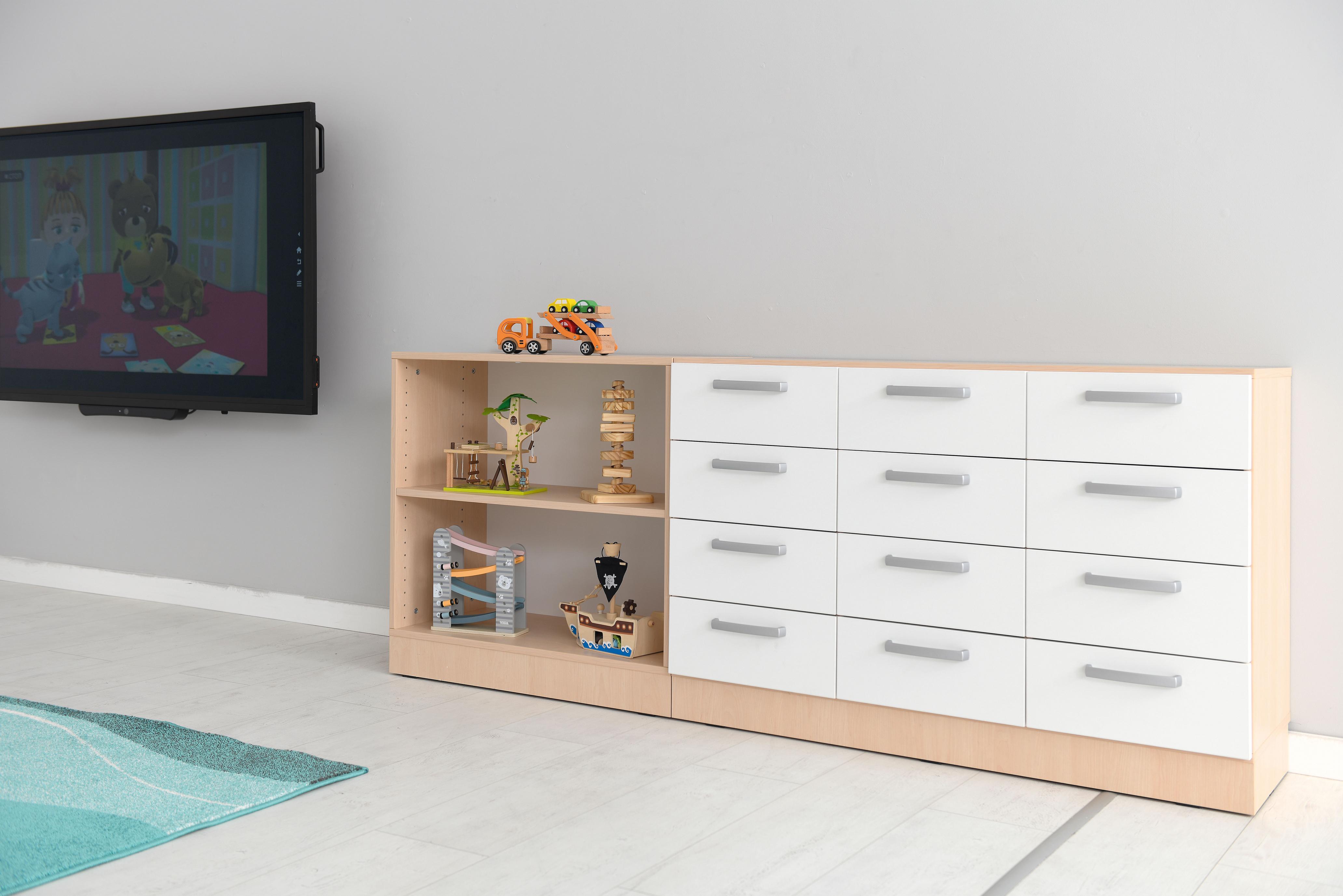 Schubladenschrank mit weißen Fronten und Spielsachen darauf.