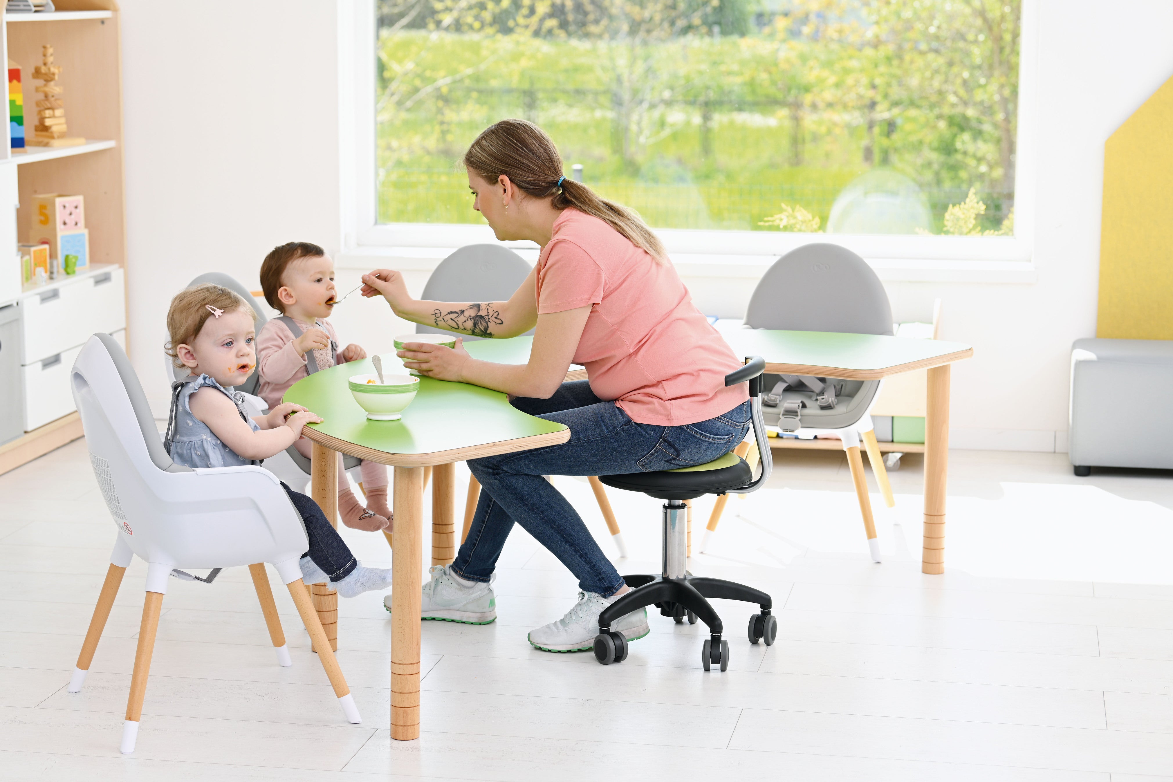 Tisch in hufeisenform für Kindergarten und Krippe im Gruppenraum, Kinder werden gefüttert