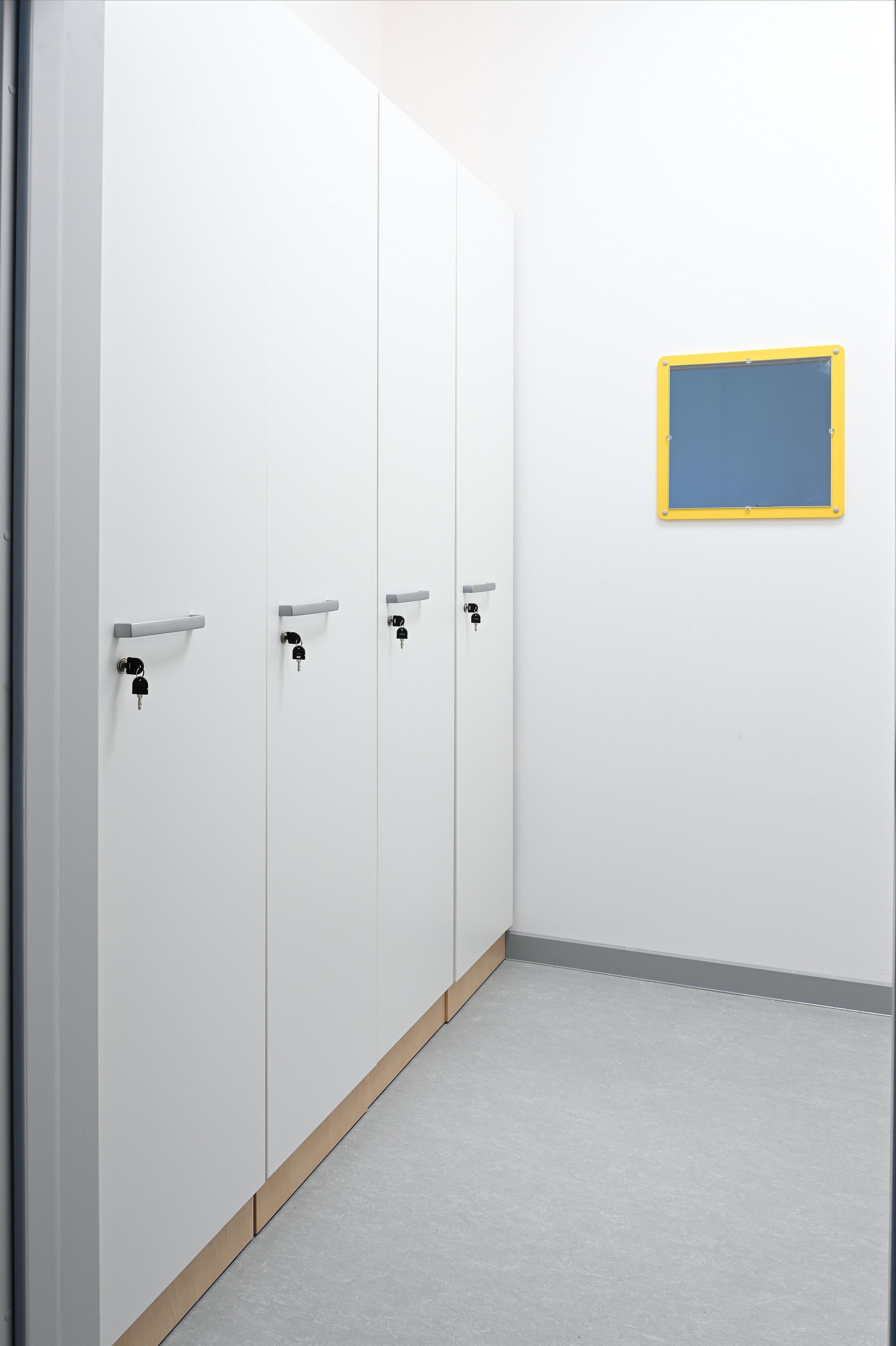 Großer, weißer Spindschrank im Gruppenraum, Ahorn-Sockel.