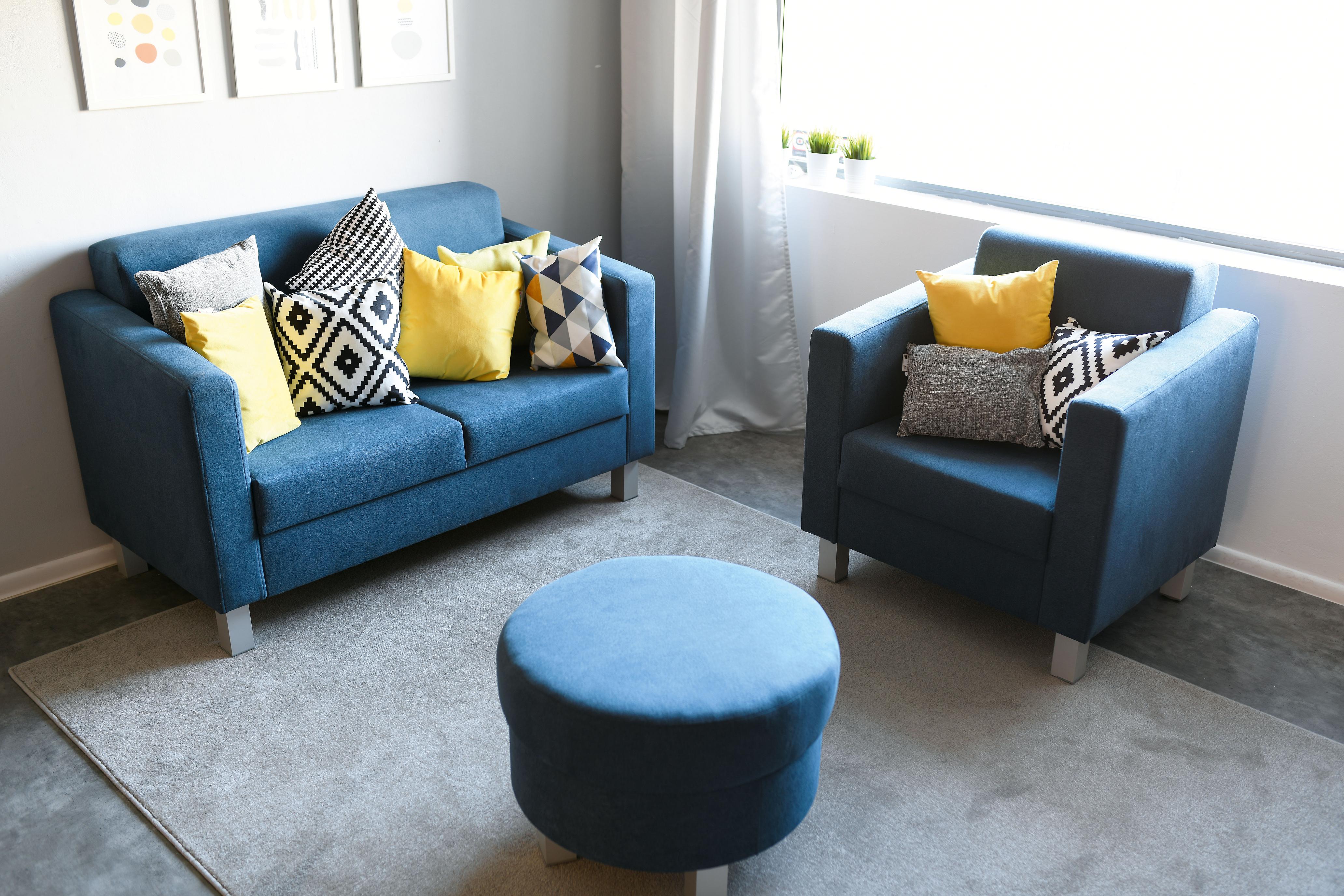 Gelbes Kissen auf blauem Sofa im Gruppenraum.