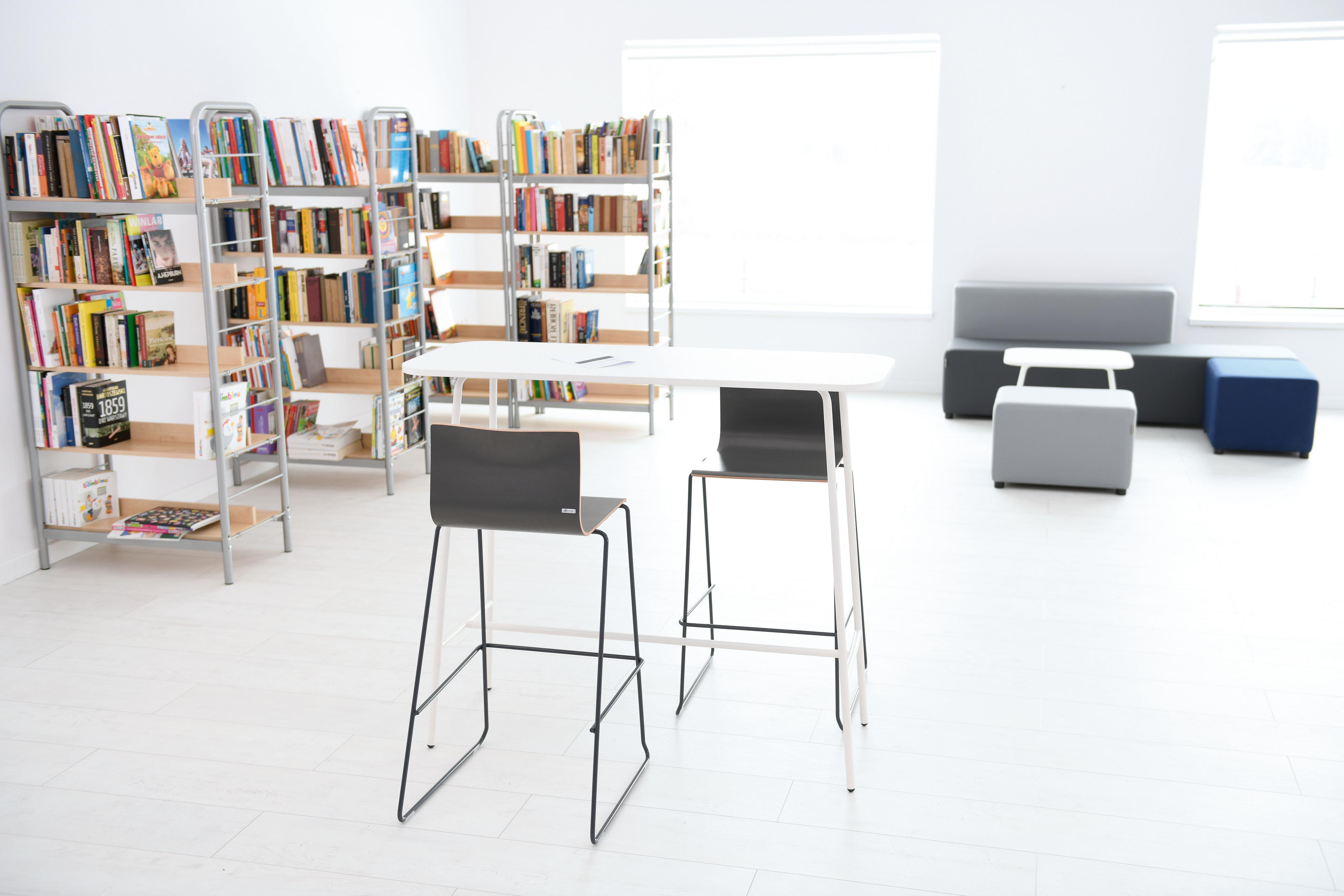 Moderner Raum mit weißem Hochtisch und Stühlen.