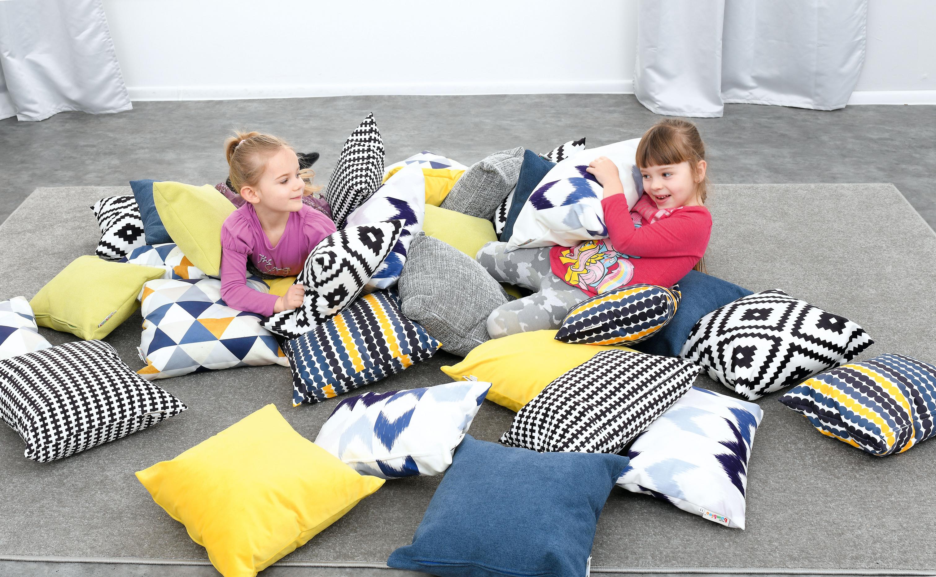 Kissen für Sitzlandschaft mit spielenden Kindern im Gruppenraum.
