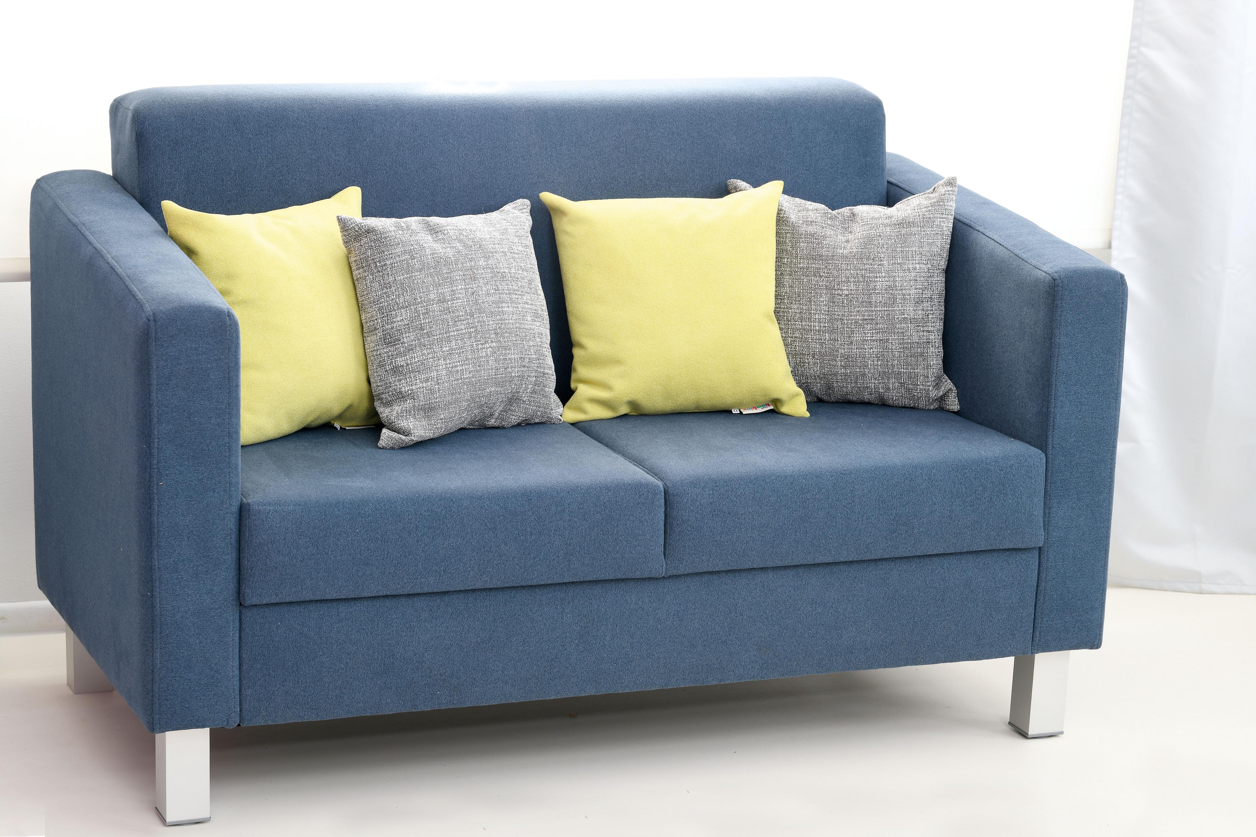 Blaues Sofa mit grauen und gelben Sitzkissen.